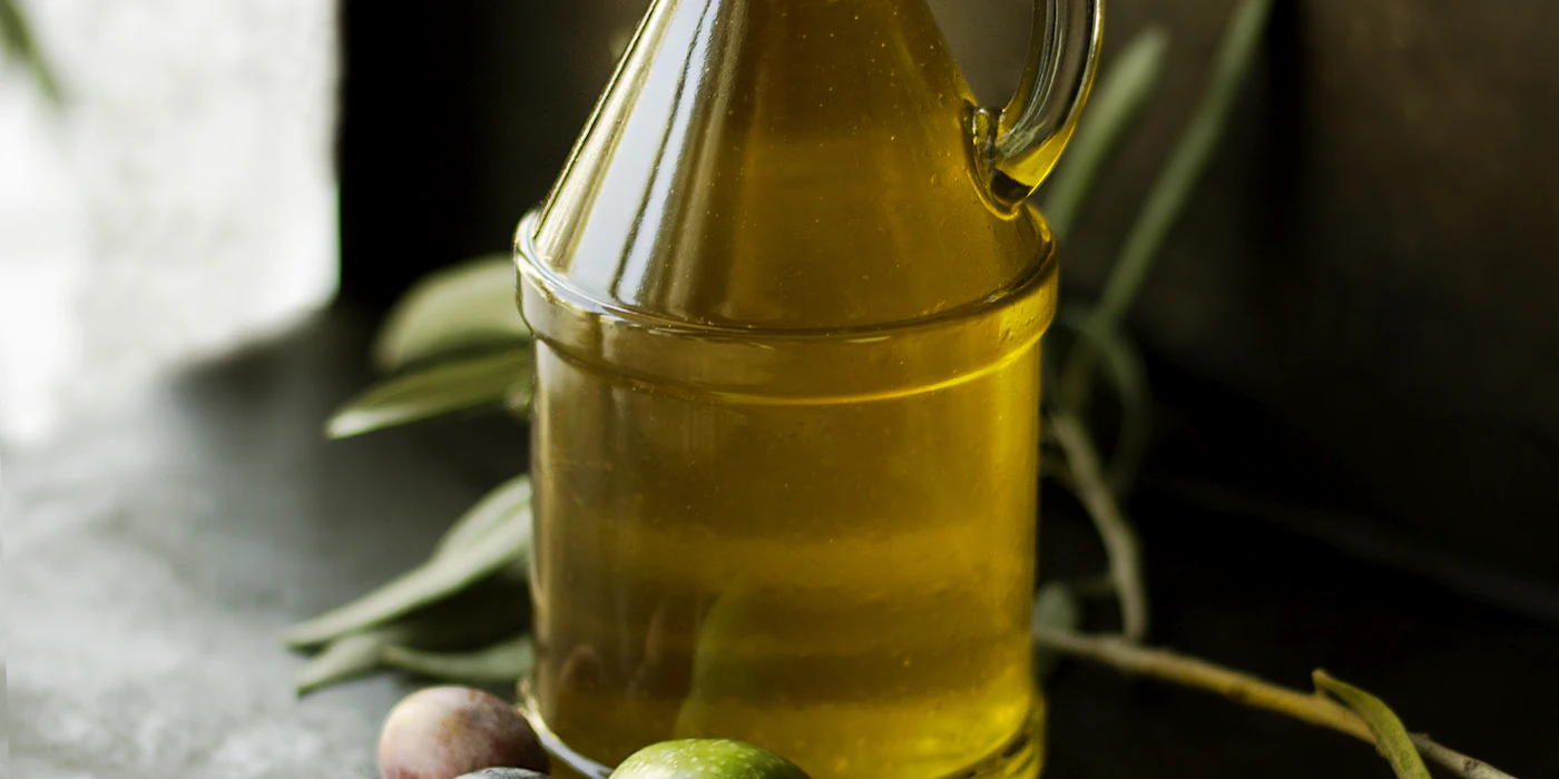 Botella de aceite de oliva con ramas de olivo